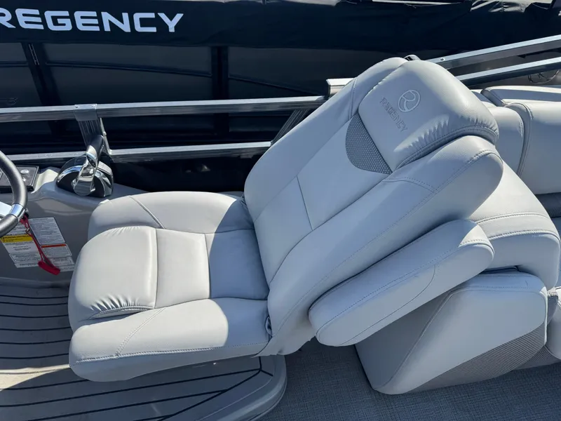 Slide: The Image of 2020 Regency 230 LE3 boat interior with plush gray seating and logo detail. - 12