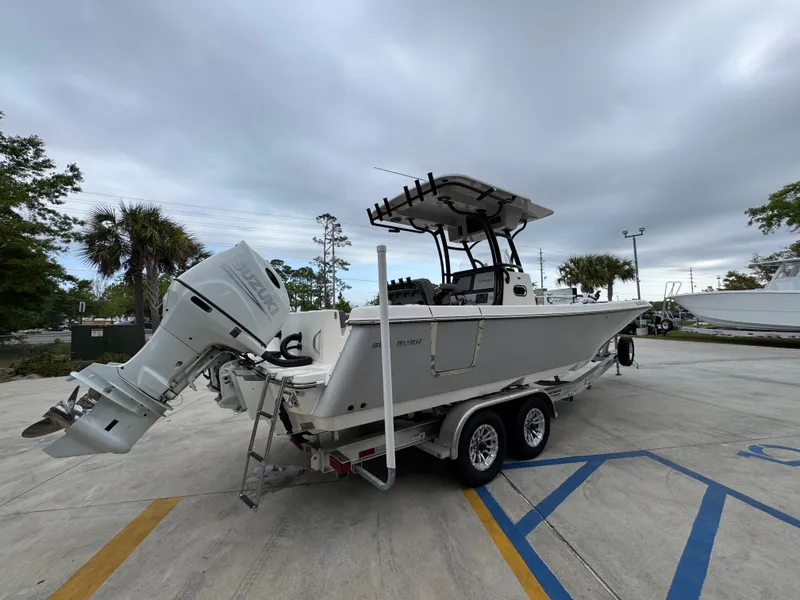 Slide: The Image of 2023 Sea Born LX26 Center Console boat on trailer, parked outdoors under cloudy sky. - 12
