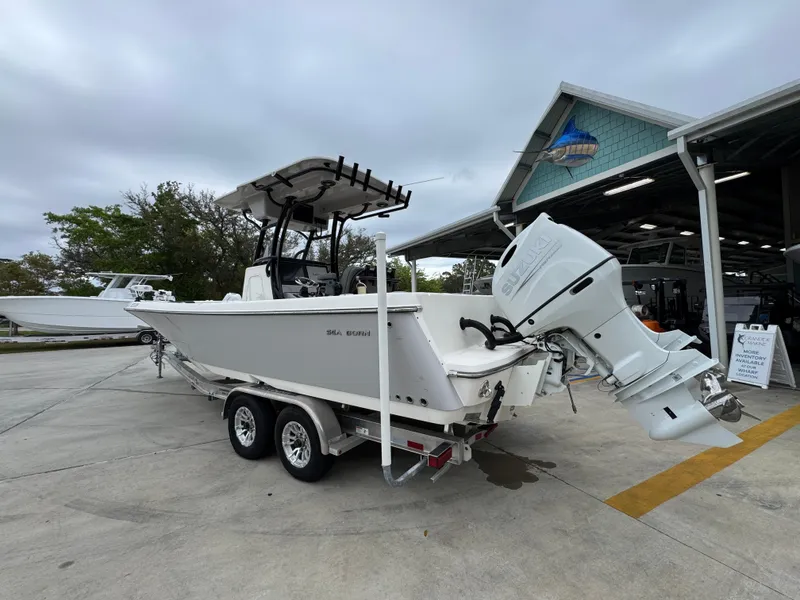 Slide: The Image of 2023 Sea Born LX26 Center Console boat on trailer, parked near a marina. - 17
