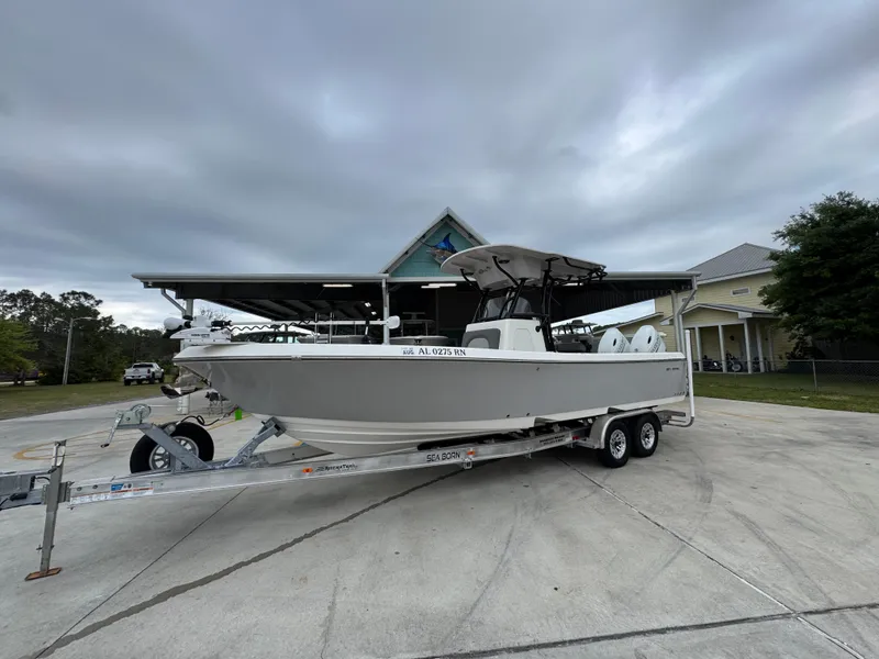 Slide: The Image of 2023 Sea Born LX26 Center Console boat on a trailer, parked outdoors. - 3