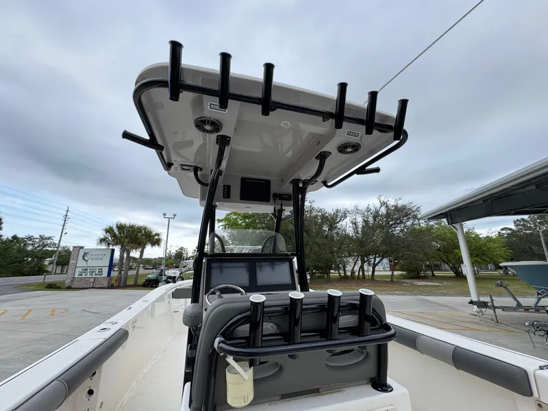 Slide: The Image of 2023 Sea Born LX26 Center Console boat with T-top and rod holders, parked outdoors. - 31