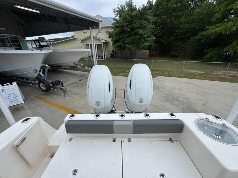 Slide: The Image of 2023 Sea Born LX26 Center Console with dual outboard engines in a boatyard setting. - 32