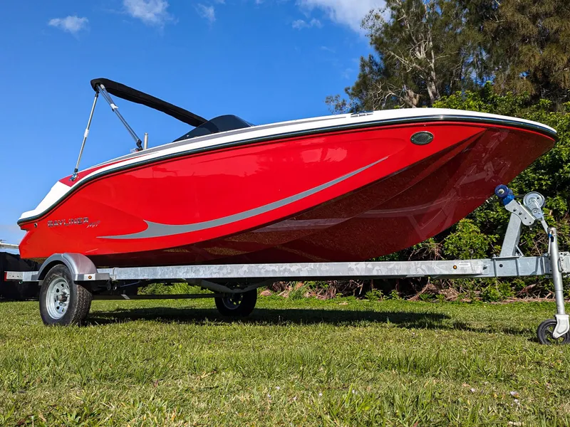 Slide: The Image of 2025 Bayliner Element M17 boat in vibrant red on a trailer, set against a clear blue sky. - 0