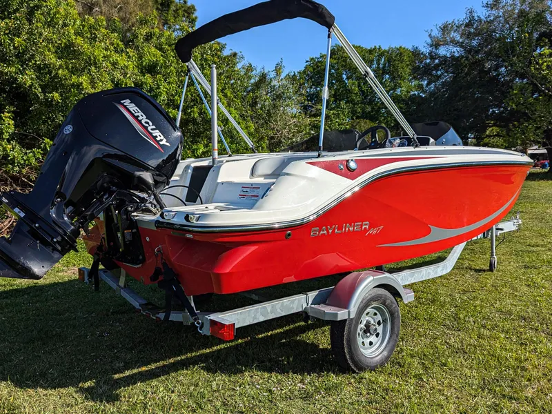 Slide: The Image of 2025 Bayliner Element M17 boat with Mercury engine on trailer, parked on grass. - 2