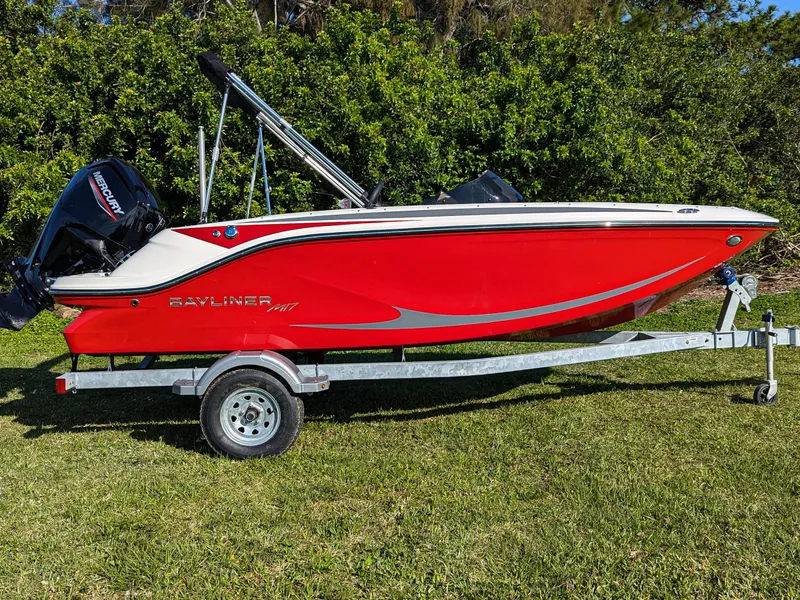 Slide: The Image of 2025 Bayliner Element M17 boat in vibrant red on a trailer, parked on grass. - 3