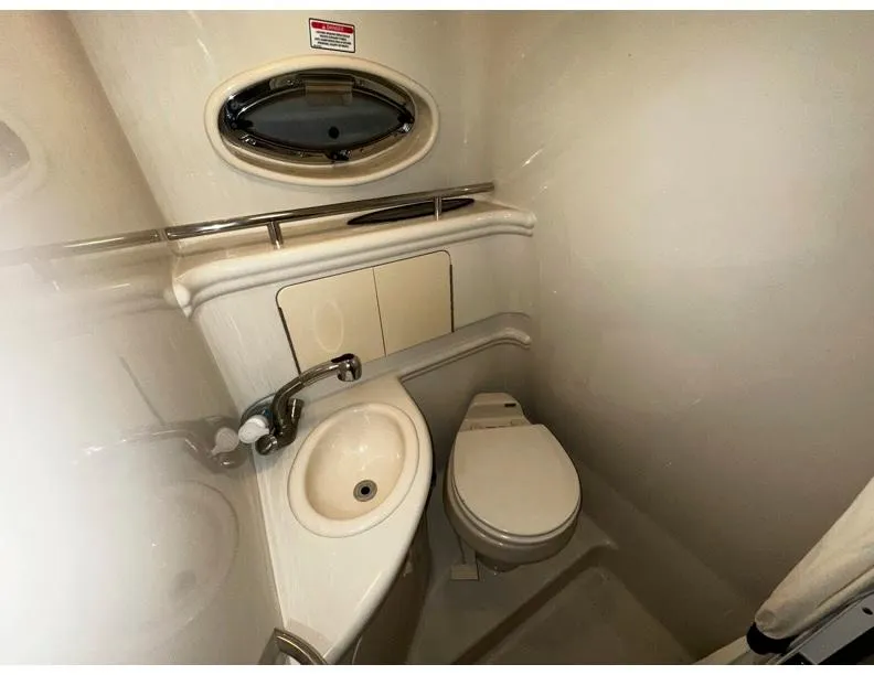 Slide: The Image of Compact bathroom in 2006 Sea Ray 280 Sundancer boat, featuring sink, toilet, and porthole window. - 11