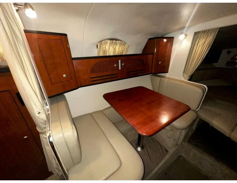 Slide: The Image of Interior of 2006 Sea Ray 280 Sundancer with wooden table and beige seating. - 9