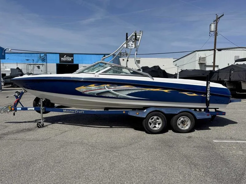 Slide: The Image of 2004 MasterCraft X30 boat on trailer, blue and white design, parked outdoors. - 0
