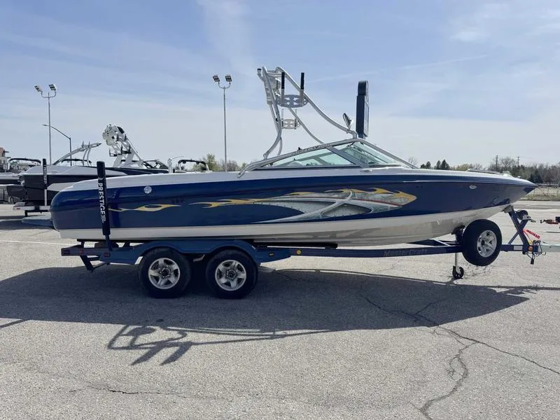 Slide: The Image of 2004 MasterCraft X30 boat on trailer, blue with graphics, parked outdoors. - 4