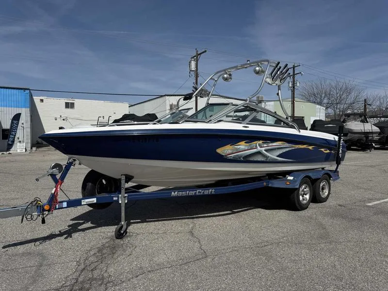 Slide: The Image of 2004 MasterCraft X30 boat on trailer in parking lot, blue and white design. - 7