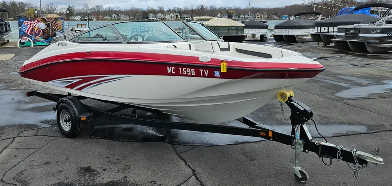 Slide: The Image of 2015 Yamaha Boats SX190 on trailer, red and white design, parked at marina. - 0