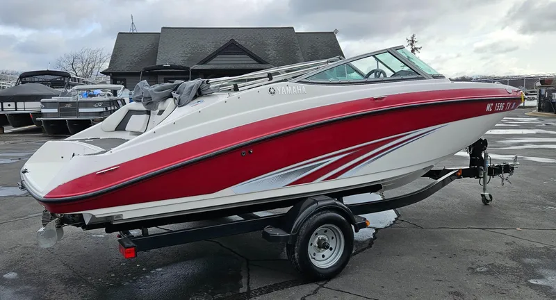 Slide: The Image of 2015 Yamaha Boats SX190, red and white, on trailer in a marina setting. - 2