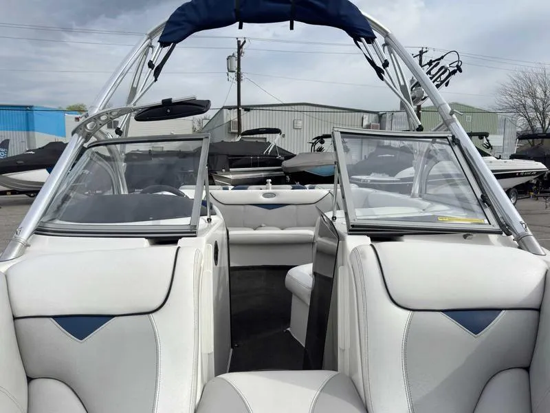 Slide: The Image of 2006 Tigé 22V boat interior with white seating and open windshield, docked outdoors. - 12