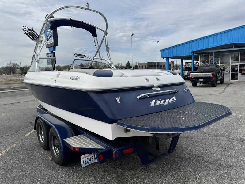 Slide: The Image of 2006 Tigé 22V boat on trailer, parked near a blue building. - 4