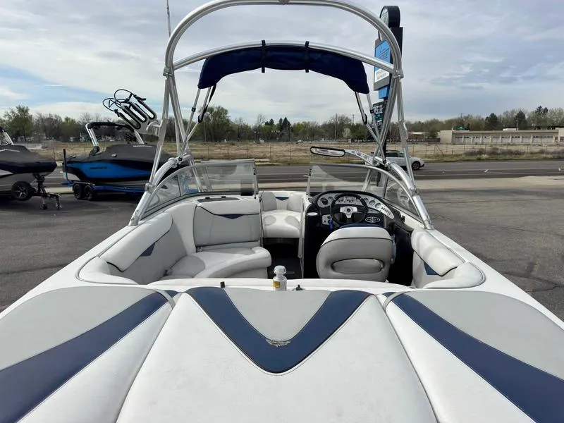 Slide: The Image of 2006 Tigé 22V boat with white and blue interior, parked outdoors. - 6