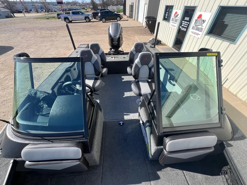 Slide: The Image of 2019 Alumacraft Trophy 175 boat interior with seating and windshield, parked outside a building. - 25