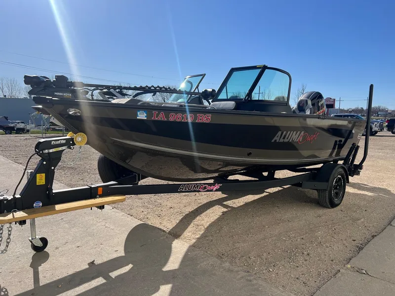 Slide: The Image of 2019 Alumacraft Trophy 175 boat on trailer under clear blue sky. - 5