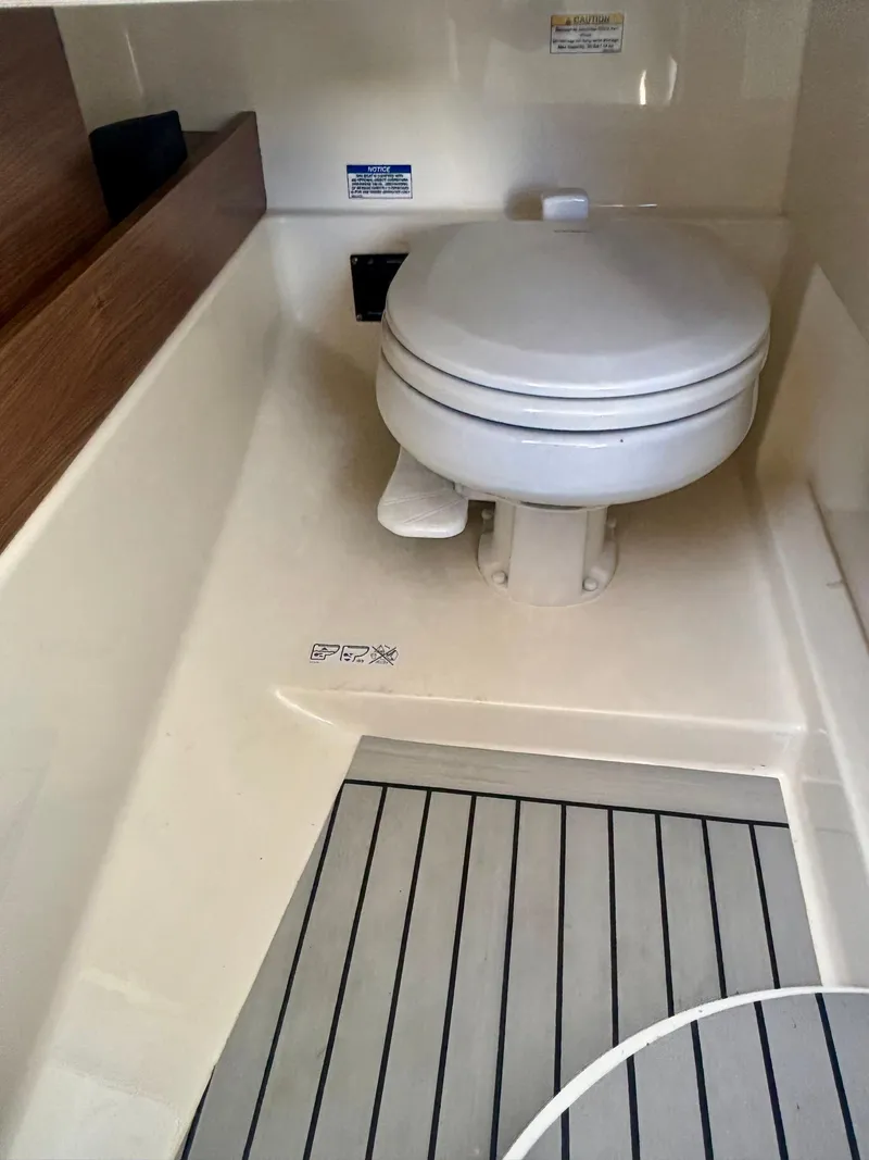 Slide: The Image of 2020 Boston Whaler 280 Vantage boat interior with toilet and wood accents. - 11