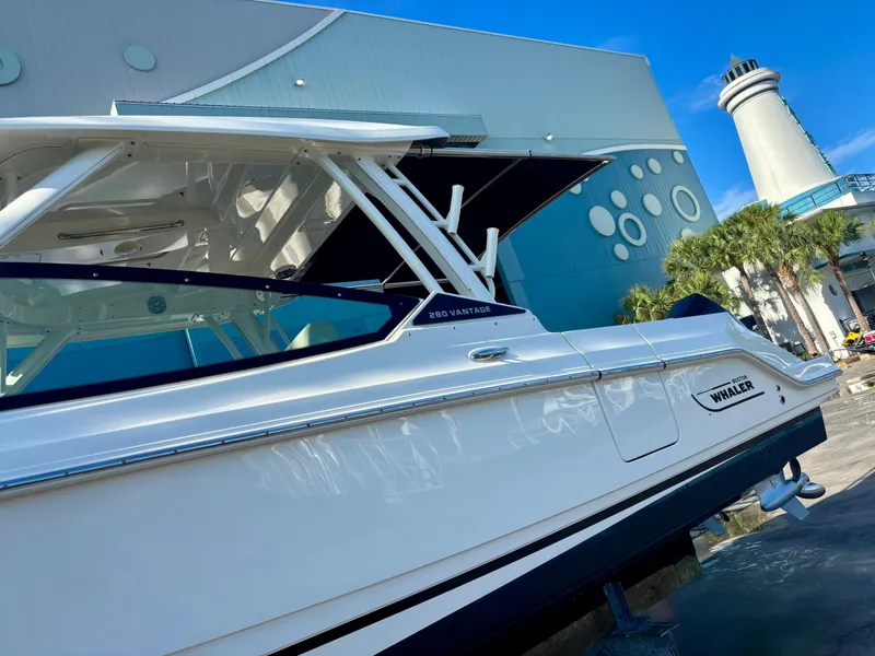 Slide: The Image of 2020 Boston Whaler 280 Vantage boat displayed outdoors near a modern building and lighthouse. - 18