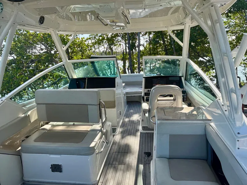 Slide: The Image of 2020 Boston Whaler 280 Vantage boat interior with seating and helm, surrounded by trees. - 2
