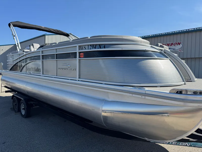 Slide: The Image of 2019 Bennington R 25 RSR pontoon boat on trailer, silver exterior, parked outdoors. - 10