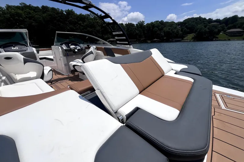 Slide: The Image of 2025 Chaparral 230 SSi boat interior with luxurious seating on a serene lake. - 11