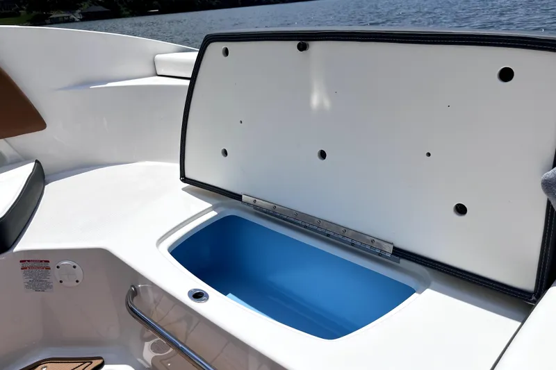 Slide: The Image of Open storage compartment on 2025 Chaparral 230 SSi boat, with blue interior, near water. - 12