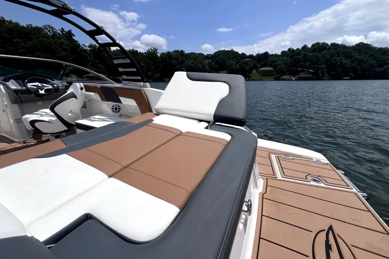 Slide: The Image of 2025 Chaparral 230 SSi boat interior with luxurious seating on a scenic lake. - 14