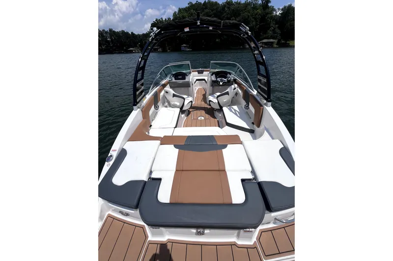 Slide: The Image of 2025 Chaparral 230 SSi boat with sleek interior design on a serene lake. - 2