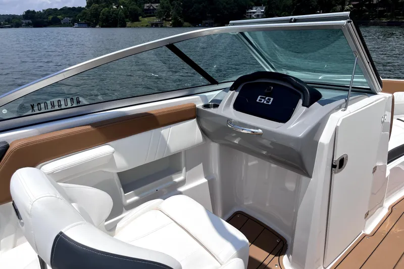 Slide: The Image of 2025 Chaparral 230 SSi boat interior with sleek dashboard and comfortable seating on a lake. - 5
