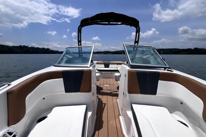 Slide: The Image of 2025 Chaparral 230 SSi boat interior with open deck, on a serene lake. - 9