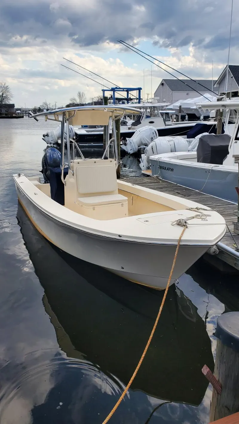 Slide: The Image of 2025 Jones Brothers 23 Cape Fisherman boat docked in a marina under cloudy skies. - 17