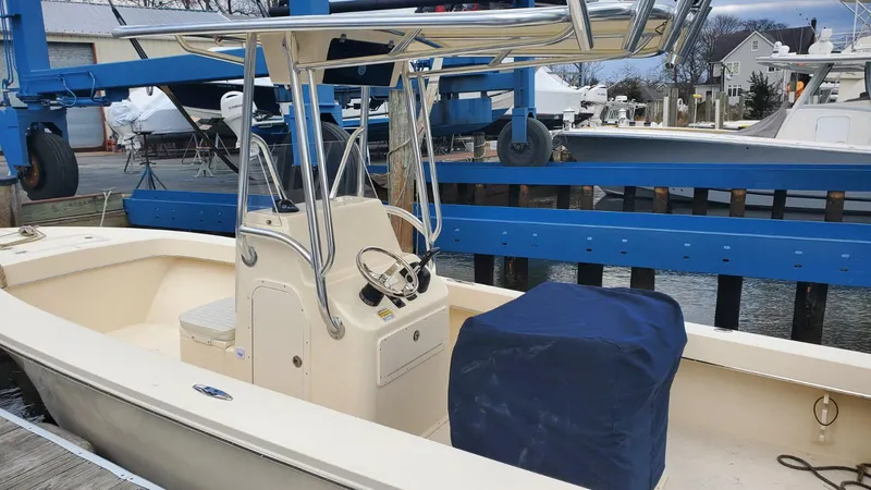 Slide: The Image of 2025 Jones Brothers 23 Cape Fisherman boat docked, featuring a center console and blue cover. - 2