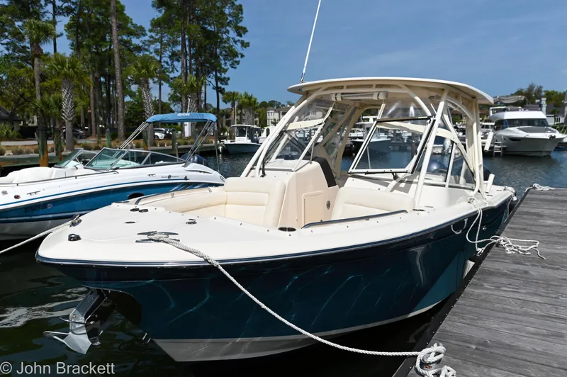 Slide: The Image of 2019 Grady-White Freedom 275 boat docked at marina, surrounded by trees and other boats. - 13