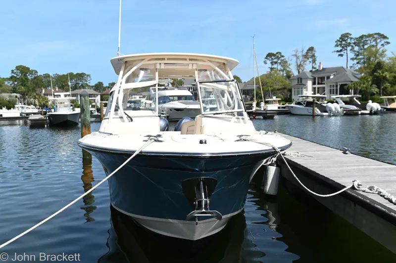Slide: The Image of 2019 Grady-White Freedom 275 boat docked at a marina, surrounded by water and trees. - 15