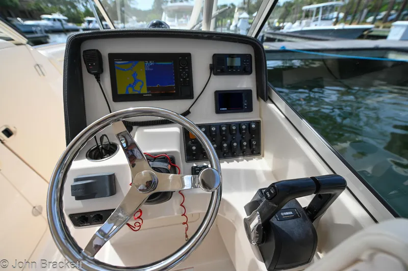Slide: The Image of 2019 Grady-White Freedom 275 boat dashboard with steering wheel and navigation equipment. - 20