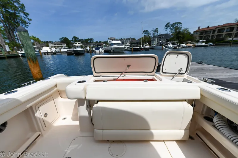 Slide: The Image of 2019 Grady-White Freedom 275 boat interior at a marina, showcasing seating and storage. - 32