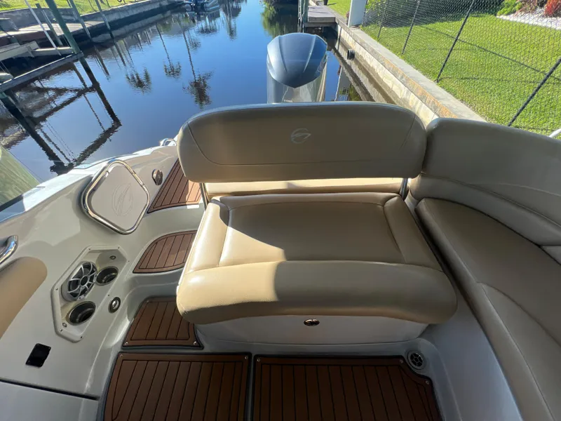 Slide: The Image of 2018 Crownline E26 XS boat interior with beige seating and wood accents by a dock. - 17