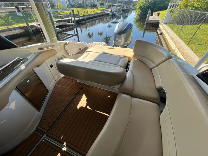 Slide: The Image of 2018 Crownline E26 XS boat interior with beige seating and wooden flooring. - 18