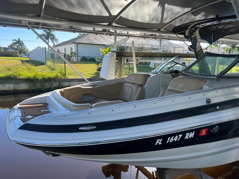 Slide: The Image of 2018 Crownline E26 XS boat docked under canopy, featuring sleek design and comfortable seating. - 22