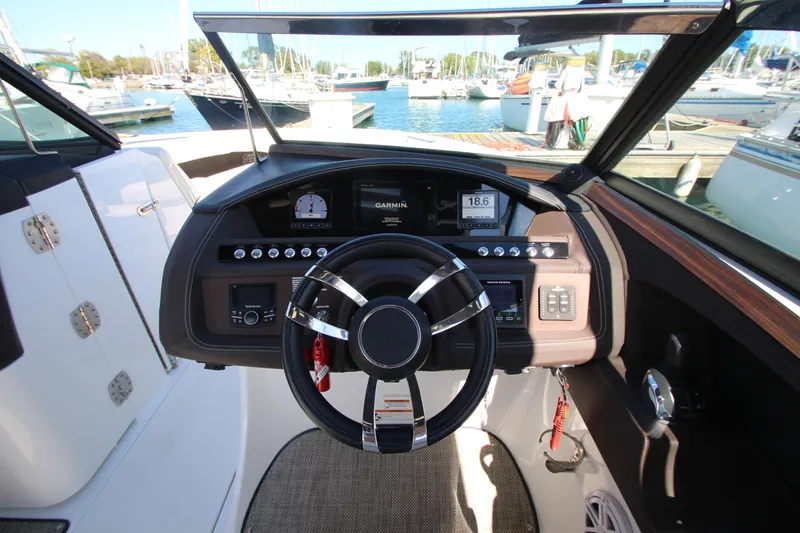 Slide: The Image of 2016 Cobalt R30 boat dashboard with steering wheel, gauges, and marina view. - 46