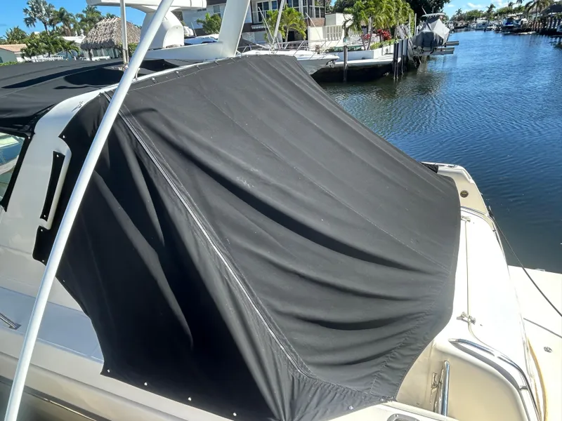 Slide: The Image of 1998 Tiara Yachts 3500 Express with black cover docked by a canal. - 15