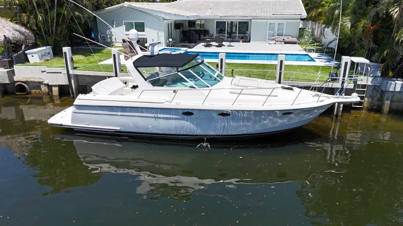 Slide: The Image of 1998 Tiara Yachts 3500 Express docked by a waterfront home with a pool. - 3