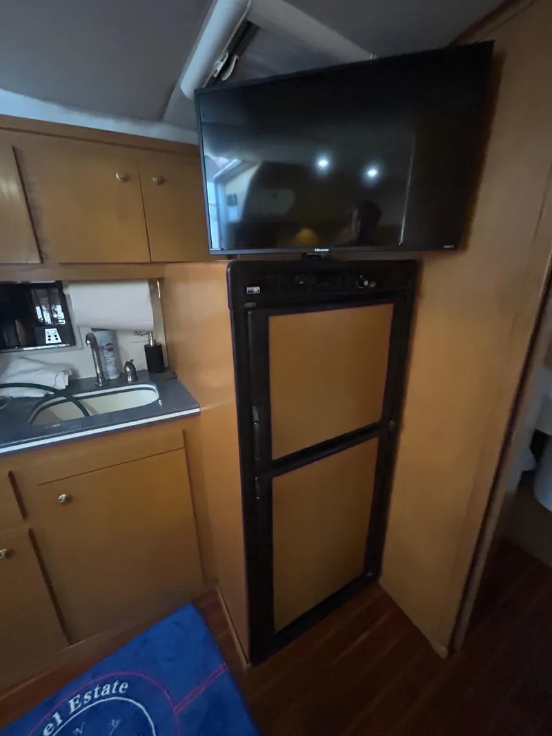 Slide: The Image of 1998 Tiara Yachts 3500 Express interior with kitchenette, fridge, and mounted TV. - 46