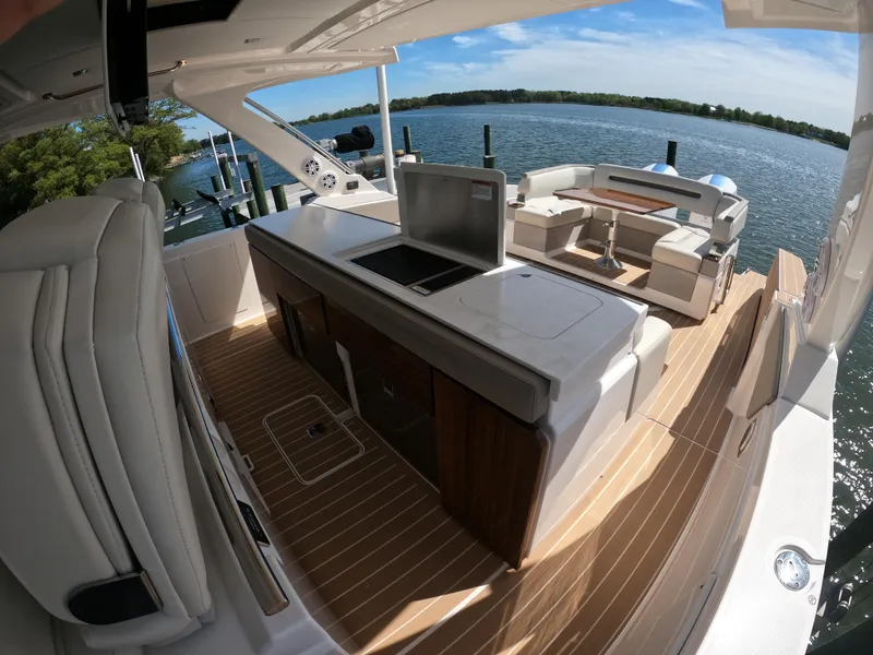 Slide: The Image of 2024 Tiara Yachts 43 LS luxury deck with seating and kitchenette, overlooking serene waters. - 8
