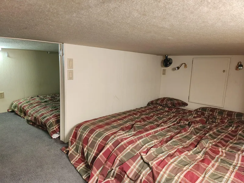 Slide: The Image of 2004 Skipperliner Inn Conspicuous Share cabin with plaid bedding and cozy lighting. - 6