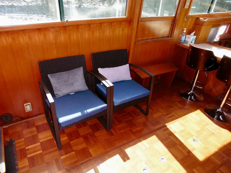 Slide: The Image of Two cushioned chairs in a wooden interior of a 1984 Ponderosa 42 boat. - 23