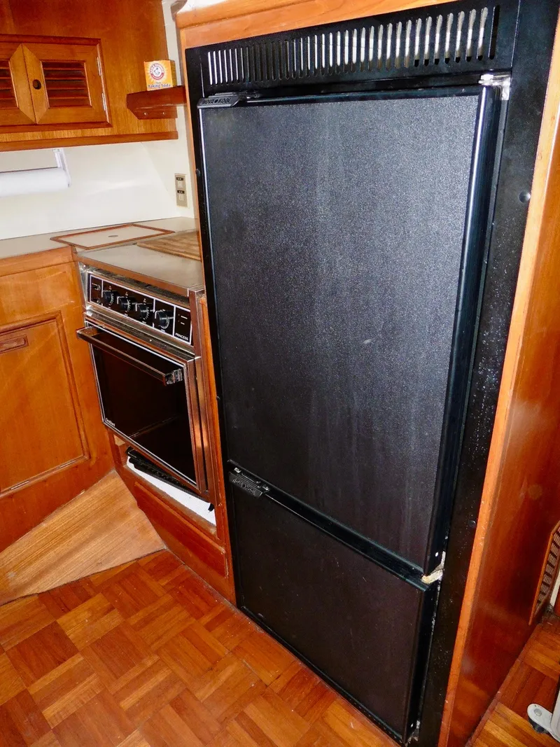 Slide: The Image of 1984 Ponderosa 42 kitchen with black fridge and wooden cabinetry. - 36