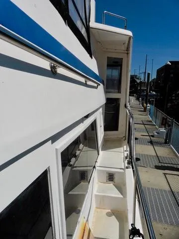 Slide: The Image of 1984 Ponderosa 42 yacht docked, showcasing side deck and railing under clear blue sky. - 7