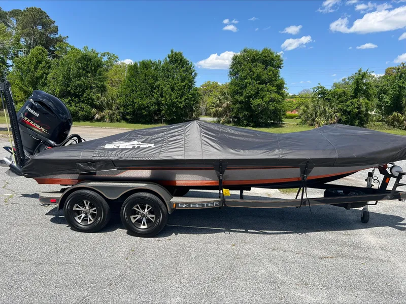Slide: The Image of 2019 Skeeter ZX225 boat with cover on trailer, parked outdoors. - 7